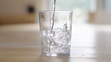 slow motion static profile shot of water being poured into backlit clear glass