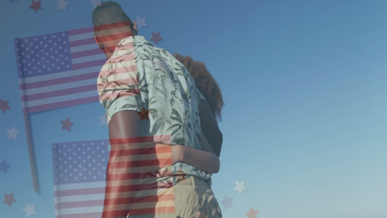 Embracing with American flag and stars, couple standing against clear blue sky