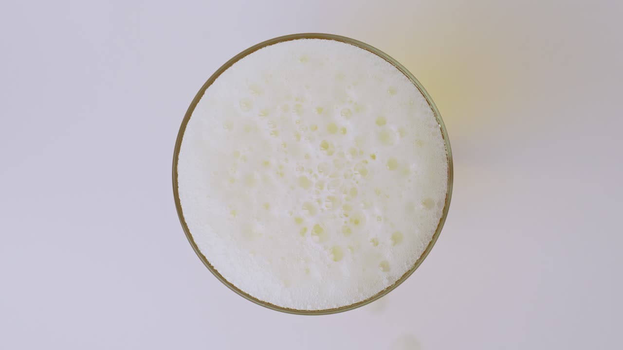 Slowmotion-optagelse af øl, der hældes i et glas, som viser bobler, skum og detaljerede væskebevægelser