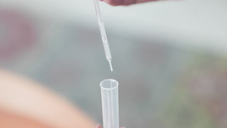 droplets of lysis buffer from pipet into plastic test tube for covid-19 test