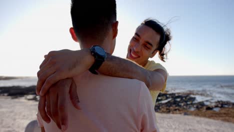 happy diverse gay male couple embracing at promenade by the sea, slow motion