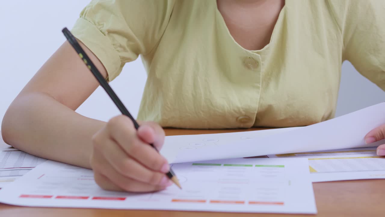 A focused individual reviews business documents highlighting data for strategic insights