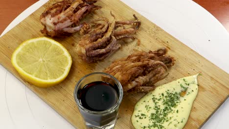 Hinzufügen-Von-Pfeffer-Zu-Einem-Holztisch-Mit-Gebratenem-Tintenfisch,-Sojasauce,-Zitrone-Und-Aioli