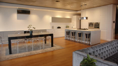 modern kitchen with dining table, transparent chairs, and island with bar stools, at home