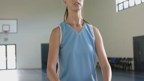 playing basketball, woman in sports jersey practicing shooting in gymnasium