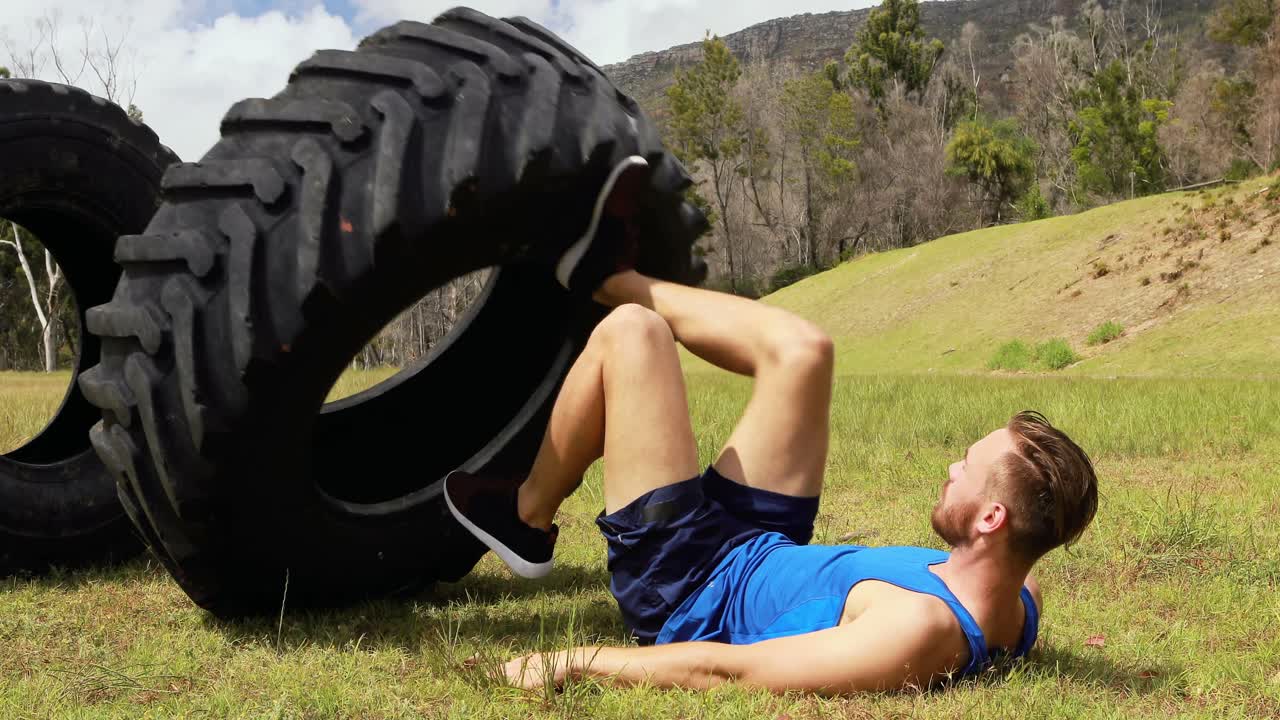 hombre en forma haciendo ejercicio con un neumático pesado durante una carrera de obstáculos