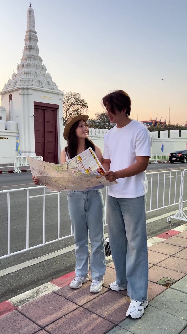 Coppia consulta una mappa accanto a un tempio bianco al tramonto, scena di strada urbana, illuminazione naturale soffusa
