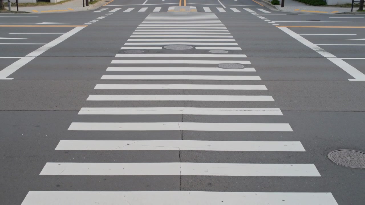 Showing painted zebra pedestrian crosswalk staying clear at curb while blue and white cars entering
