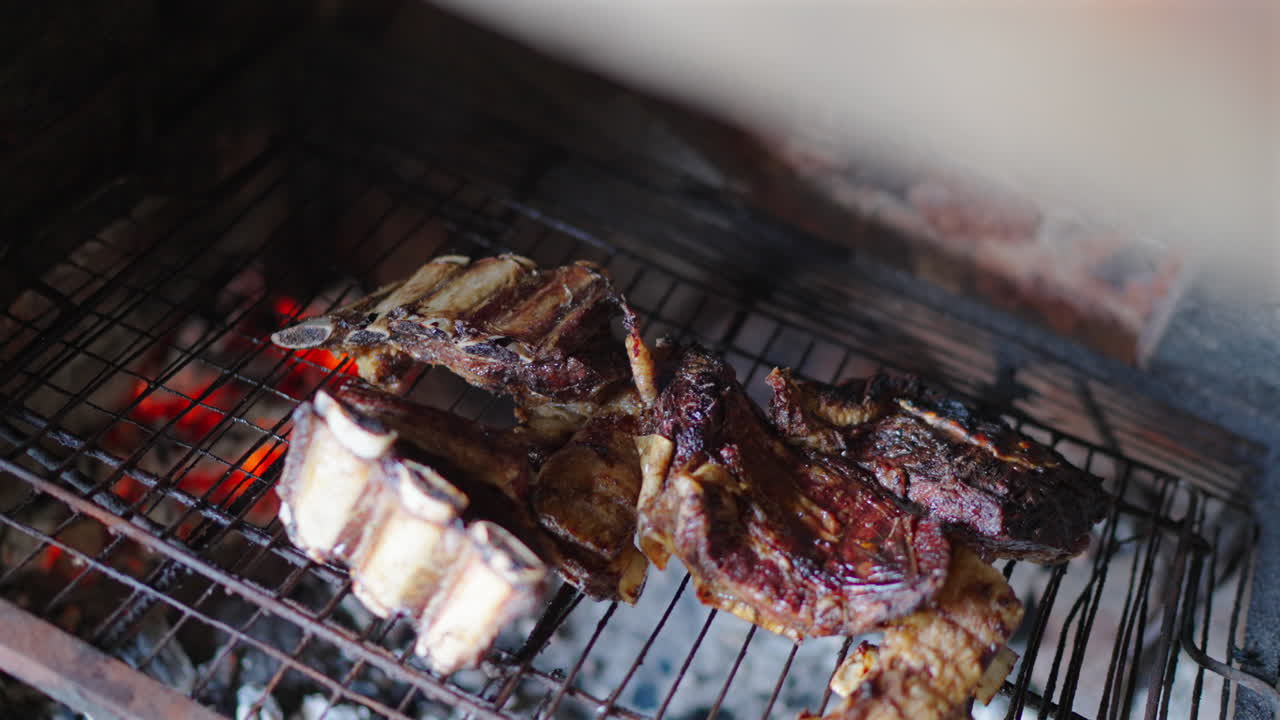 Barbecue scene of the traditional Asado Argentino meat sizzling over glowing coals.