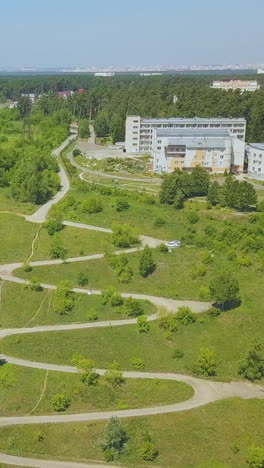 hairpin curves on picturesque green hill and newly wedded couple against dwelling buildings on nice sunny day aerial view