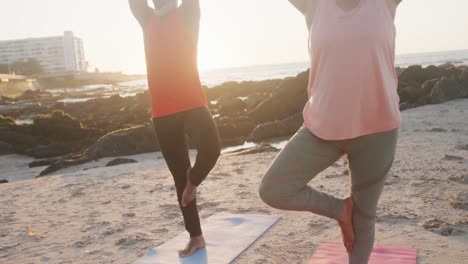 happy senior african american couple doing yoga, meditating at beach, slow motion