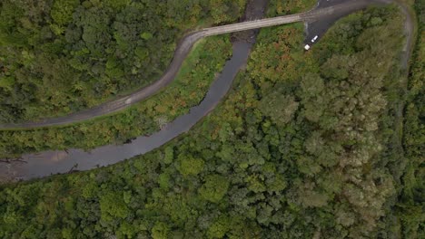 vista aérea de arriba hacia abajo siguiendo el curso de un río selvático con un pequeño puente que cruza