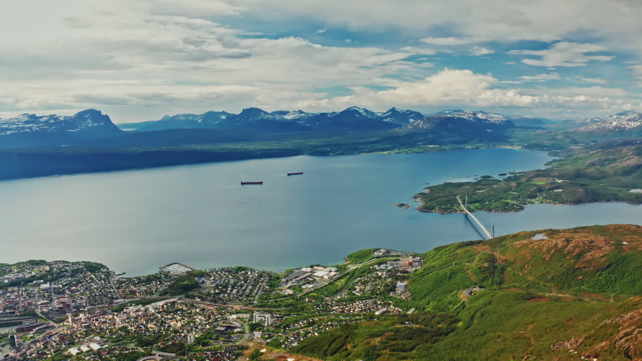 Aerial drone shot over the city of Narvik in Norway. High view of the scenic green landscape, the sea and the nordic fjords.