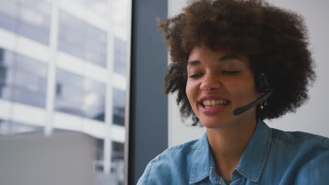 Junge-Geschäftsfrau-Im-Modernen-Büro,-Die-Mit-Einem-Drahtlosen-Headset-Am-Laptop-Arbeitet