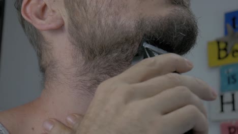 A-Caucasian-man-is-trimming-his-facial-hair-with-an-electric-razor-to-look-groomed