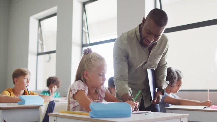 Video of happy african american male teacher helping in exercise to caucasian girl