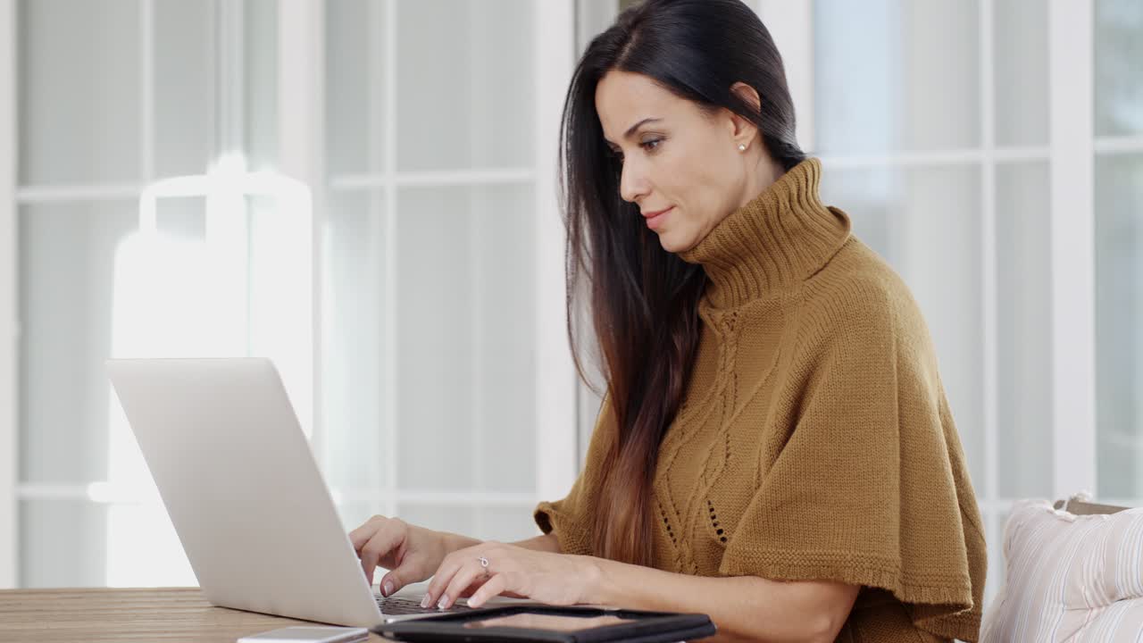mujer atractiva sentada escribiendo en una computadora portátil