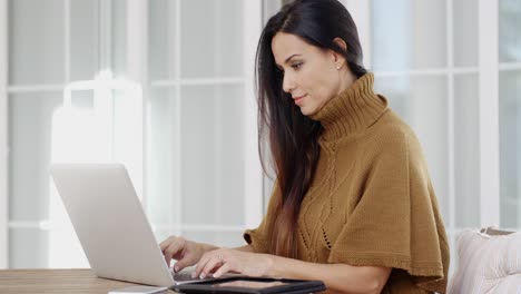 mujer atractiva sentada escribiendo en una computadora portátil