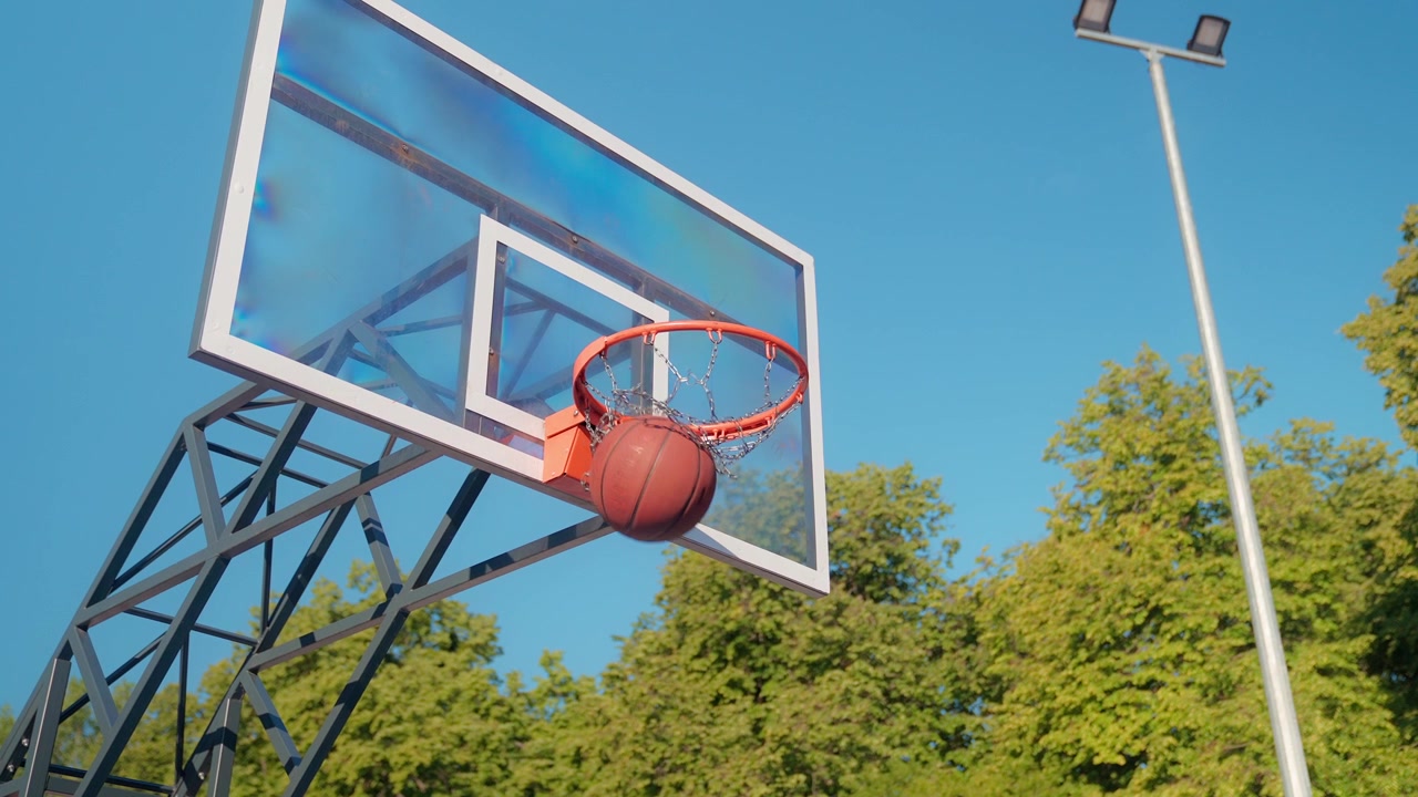 Palla da basket che entra nel canestro su un campo all'aperto al rallentatore.