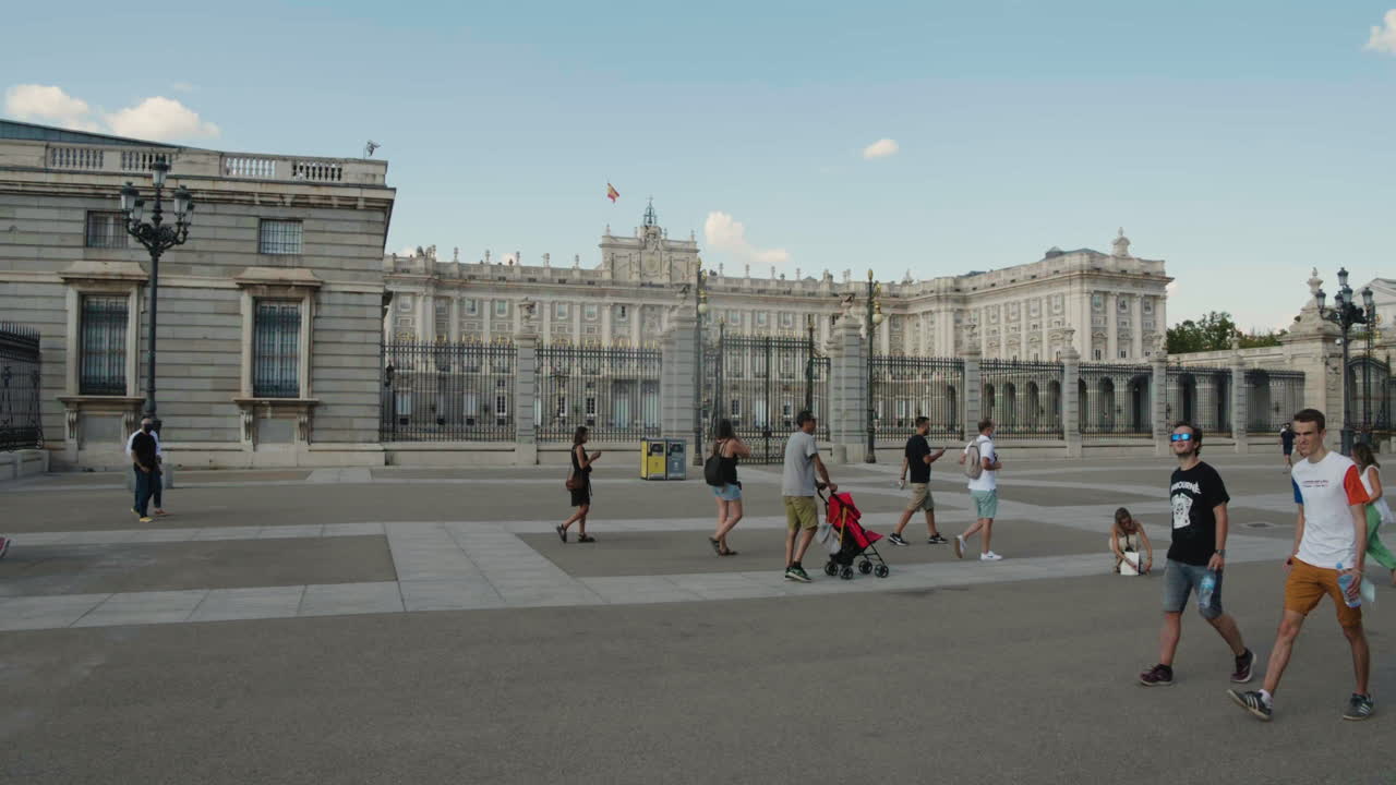 Several People Passing By The Royal Palace Of Madrid During Daytime In Spain. Static Shot