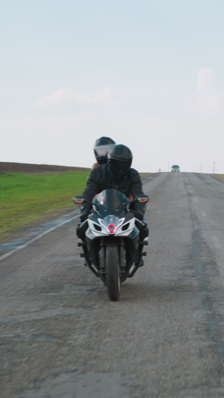 Empty rural road between spring fields and couple enjoying motoriding at picturesque countryside under sky with white clouds slow motion