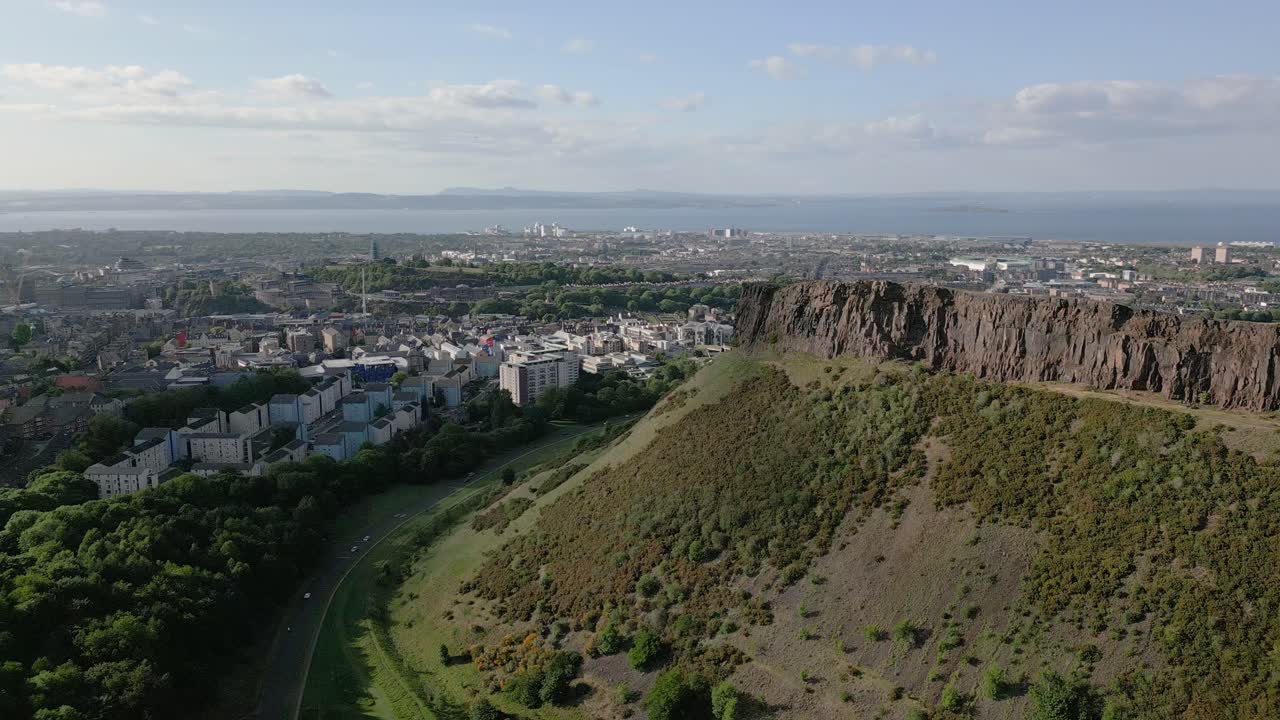 Aerial orbit around the local iconic Arthur's Seat at Holyrood Park with surrounding Edinburgh city centre, Edinburgh, Scotland, UK