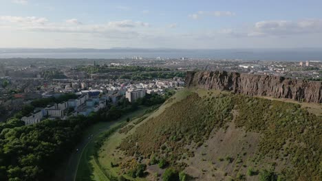aerial orbit around the local iconic arthur's seat at holyrood park with surrounding edinburgh city centre, edinburgh, scotland, uk