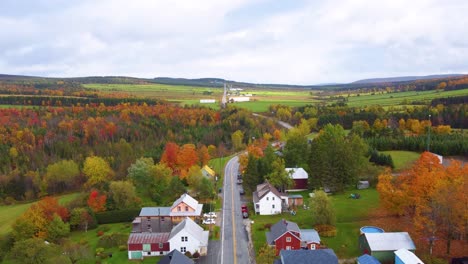 dolly in drone shot above typical canadian town with autumn colors in region of estrie, quebec, canada