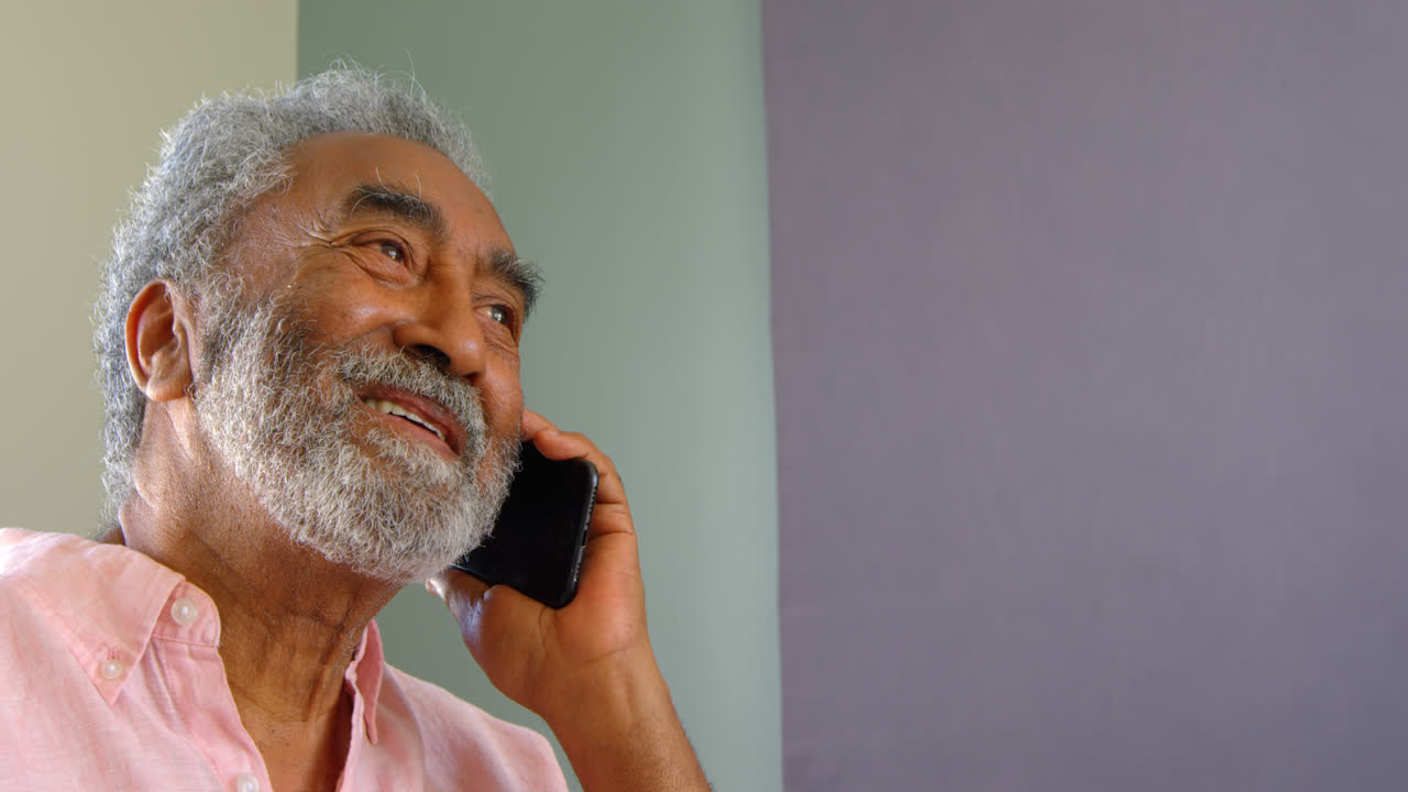 Side view of old asian senior man talking on mobile phone at home 4k
