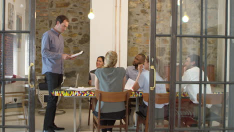 Young-man-addressing-a-team-meeting-in-a-boardroom