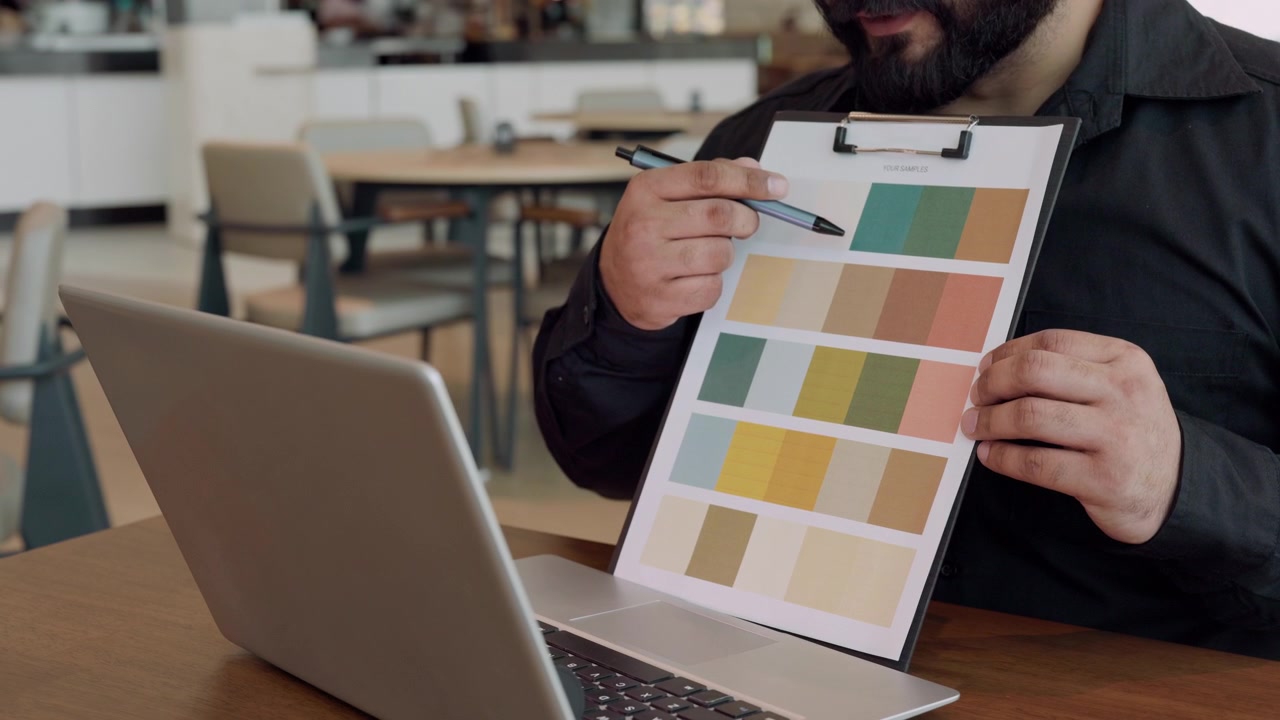 Diseñador seleccionando paleta de colores de una carta de muestras en la oficina