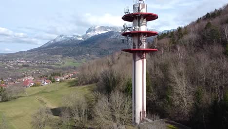 Drone-shot-moving-in-on-an-Antenna-with-Villages-and-Mountains-in-the-background