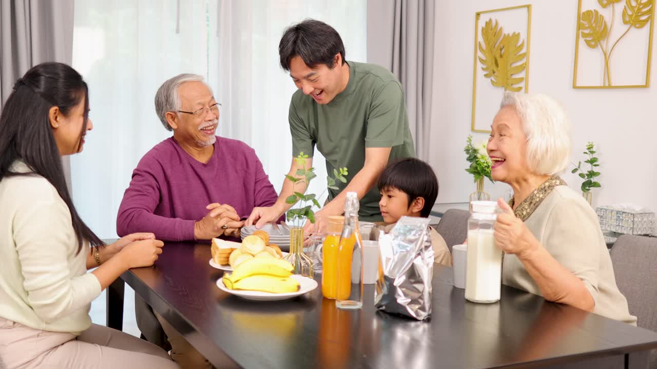 Four generations share a cheerful breakfast in a bright, cozy dining room with natural lighting