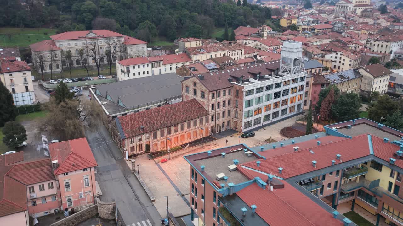 Riprese aeree con drone che mostrano un avvicinamento fluido e rotante verso il Lanificio Conte, un complesso industriale storico a Schio, Italia.