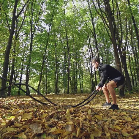 man with battle rope in park