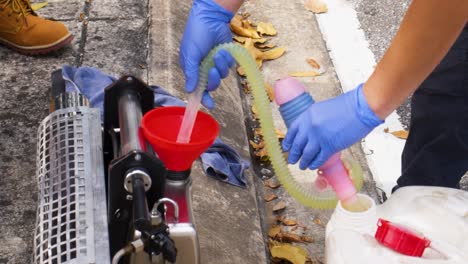 worker preparing fogging service by pouring chemical insecticides into machine, southeast asia