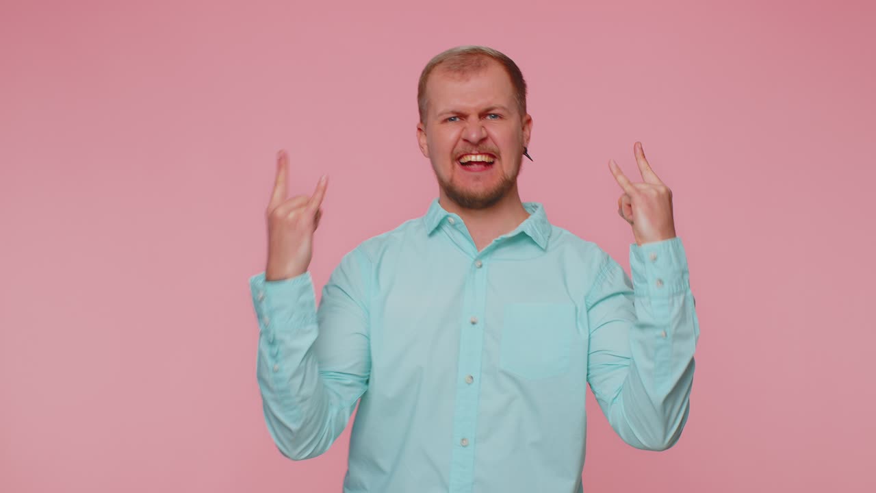 Overjoyed happy man showing rock n roll gesture by hands cool sign shouting yeah with crazy face