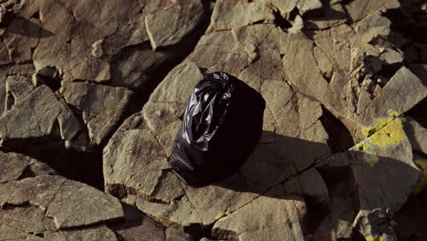 Ein-Schwarzer-Müllsack-Lag-An-Einem-Felsigen-Strand