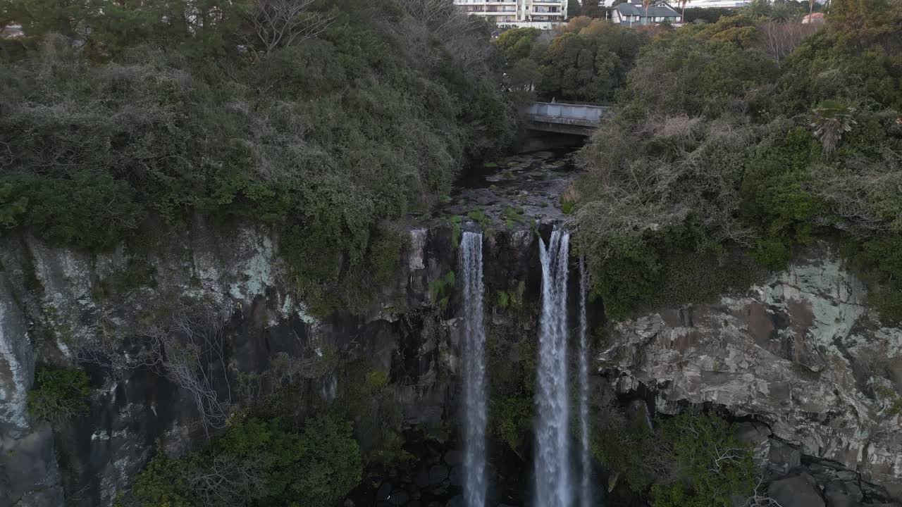 Drone aerial view in South Korea flying over a waterfall falling into the sea rocky area jeju island