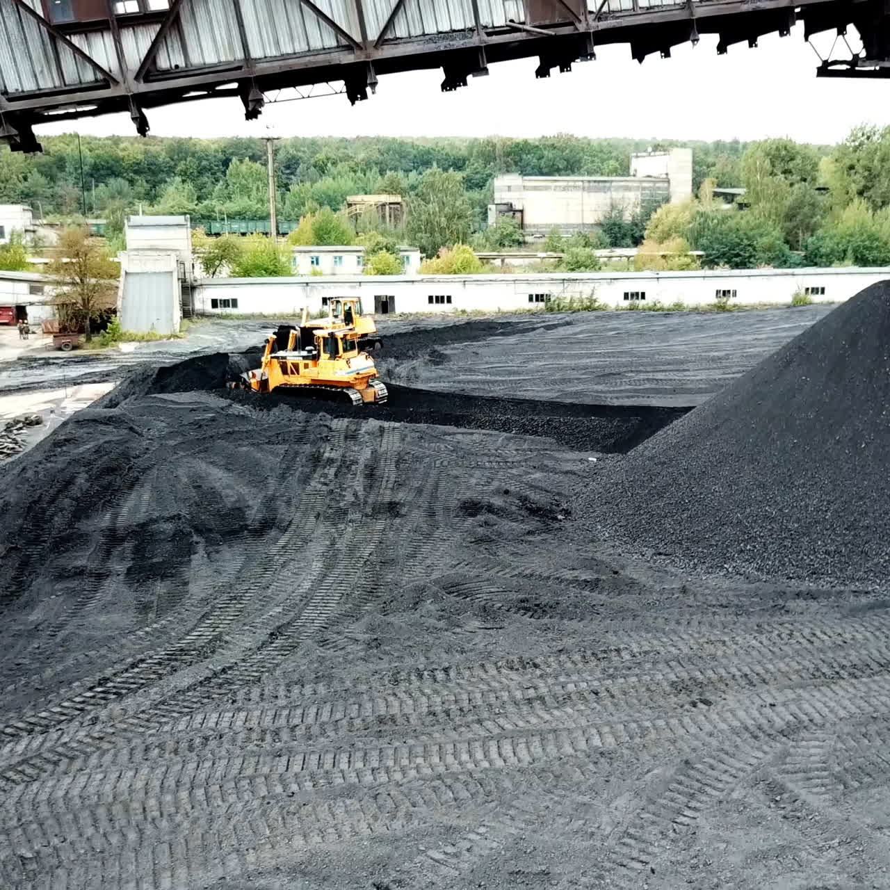 Bulldozer pushing coal on enormous coal pile. Extractive industry. Aerial view.