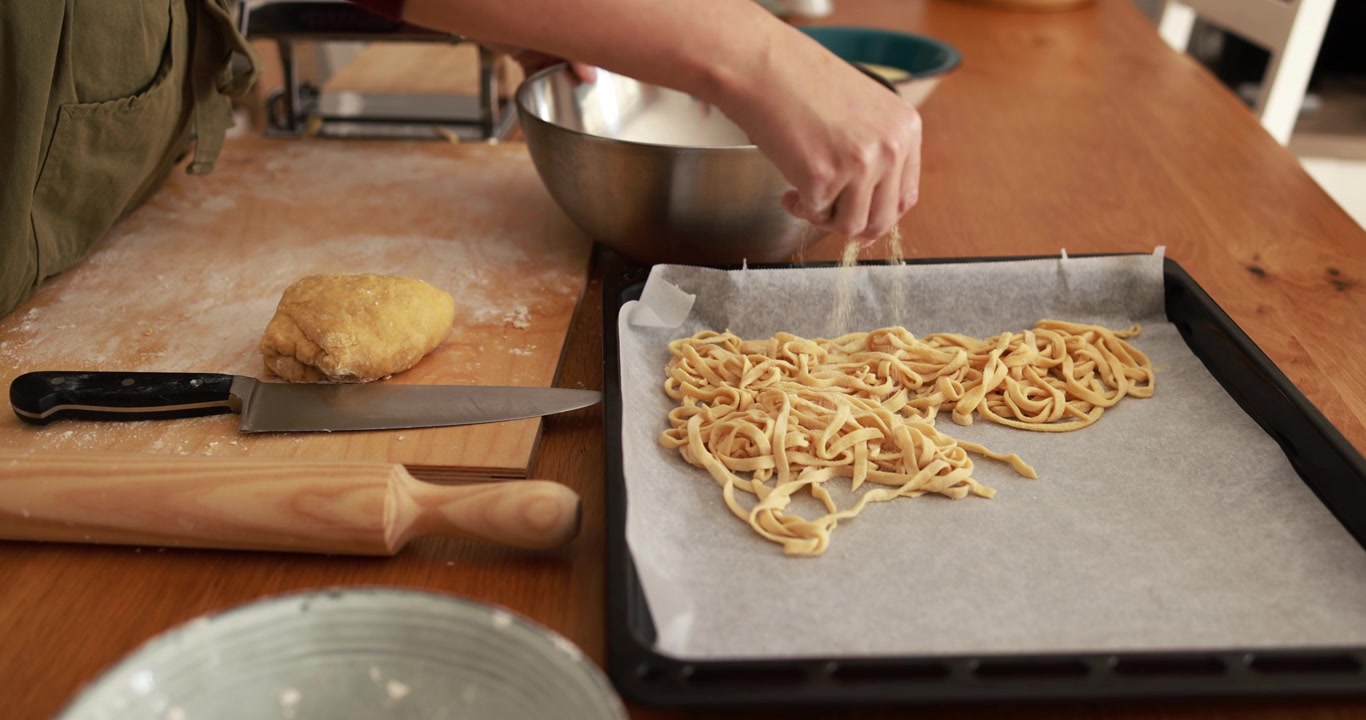 Persona che prepara pasta fresca fatta in casa su un tavolo di legno