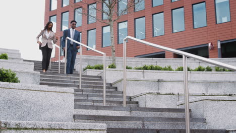 businessman and businesswoman commuting to work walking down steps outside office building