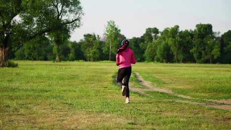 The-girl-runs-at-sunset-in-the-Park-along-the-pond-and-listening-to-music-in-headphones