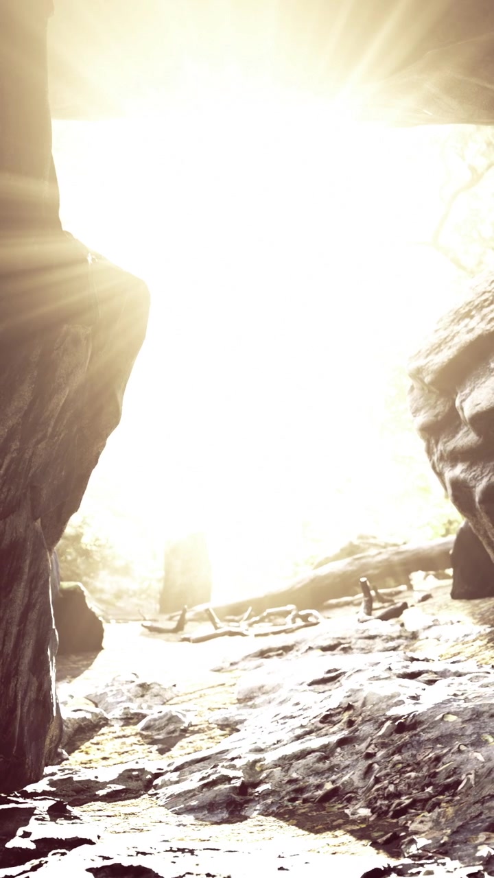 Light shines through cave entrance at midday creating bright scene
