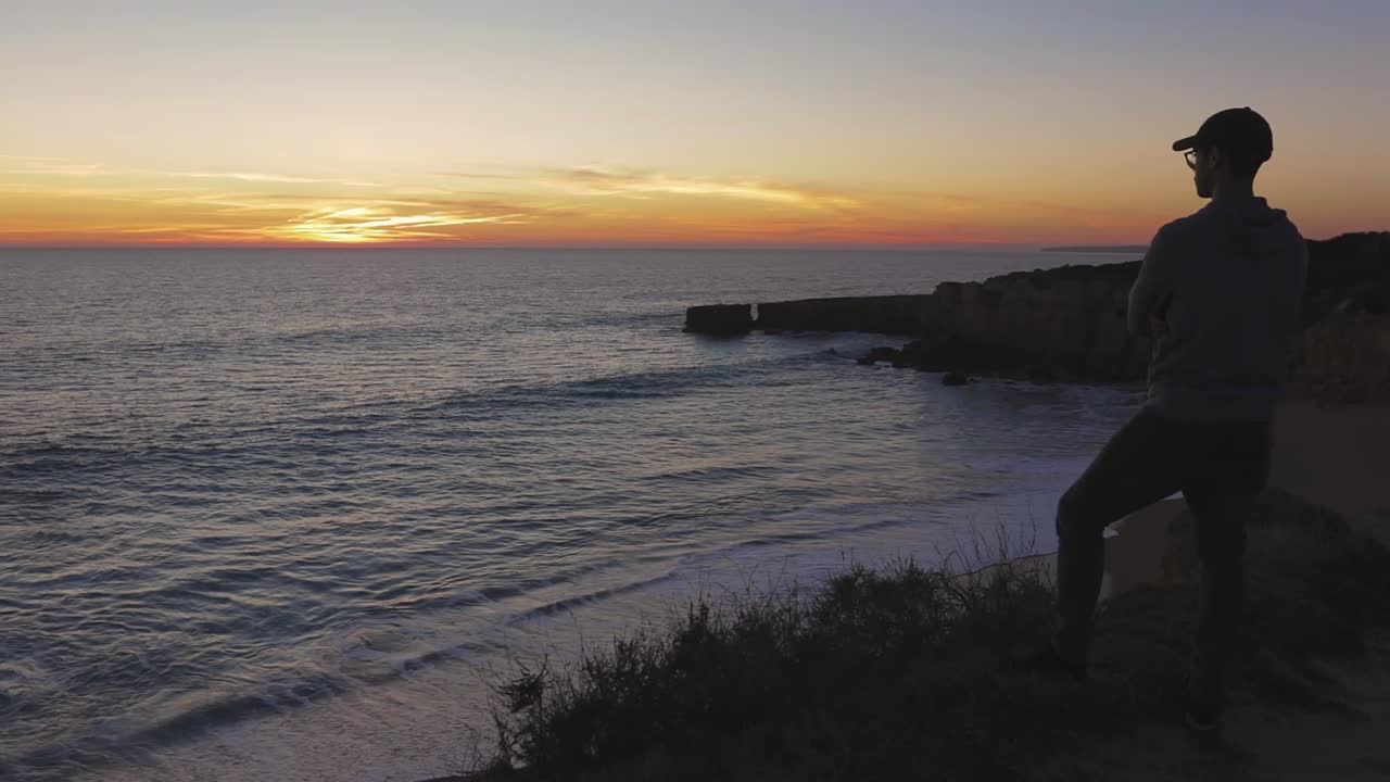 Young Adult calmly enjoying a beautiful sunset overlooking the beach.