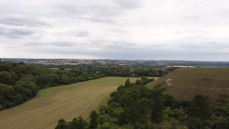 Aerial-high-revealing-huge-green-field-just-cut-in-Hitchin,-Hertfordshire,-England,-Uk