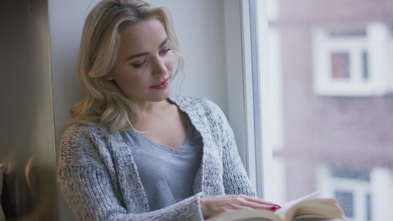 Donna che legge un libro vicino alla finestra