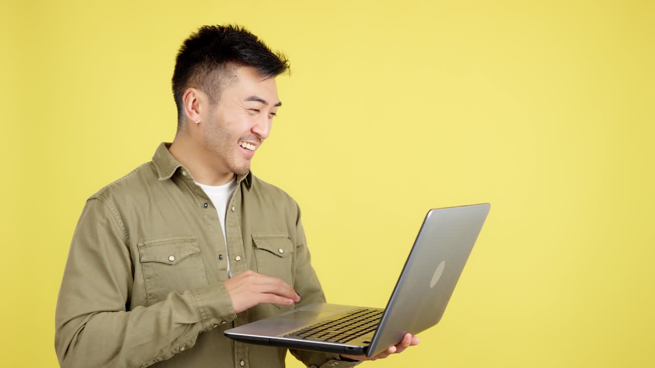 Asian Man Using Laptop on Yellow Background