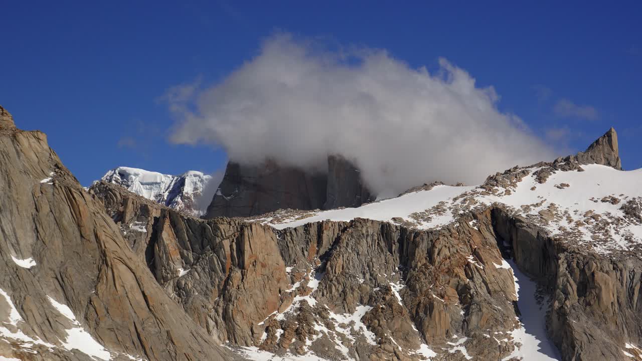 Time-lapse of Cerro Torre in Patagonia surrounded by thick, rolling clouds and a deep blue sky in Patagonia