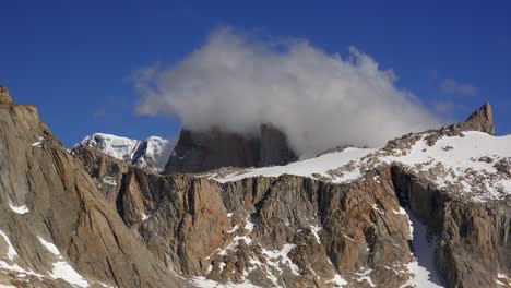 time-lapse of cerro torre in patagonia surrounded by thick, rolling clouds and a deep blue sky in patagonia